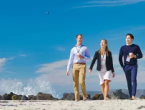 Three meeting attendees walking on the beach