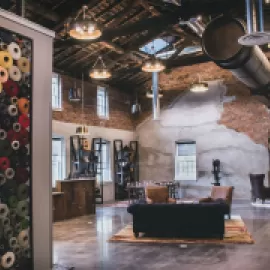 Photo: The hotel complex is uniquely Amana from the customer’s first step into the lobby. The design team incorporated old equipment from the mill. On the left, the yarn wall is a nod to the woolen production that still occurs on site. Credit: Sara Montgomery