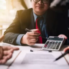 Person with a calculator examining a contract.
